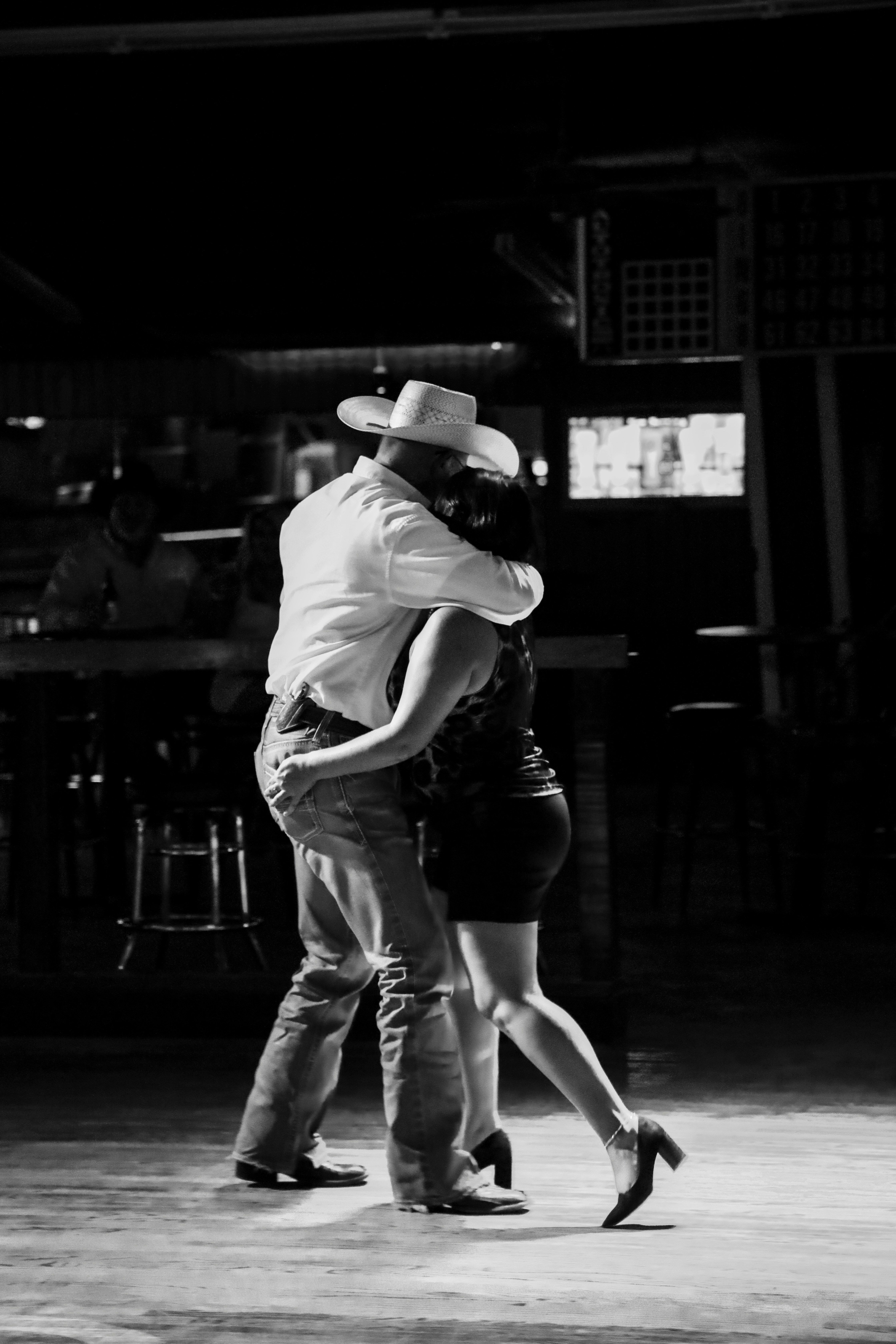 Couple two-stepping at a honky tonk, black and white